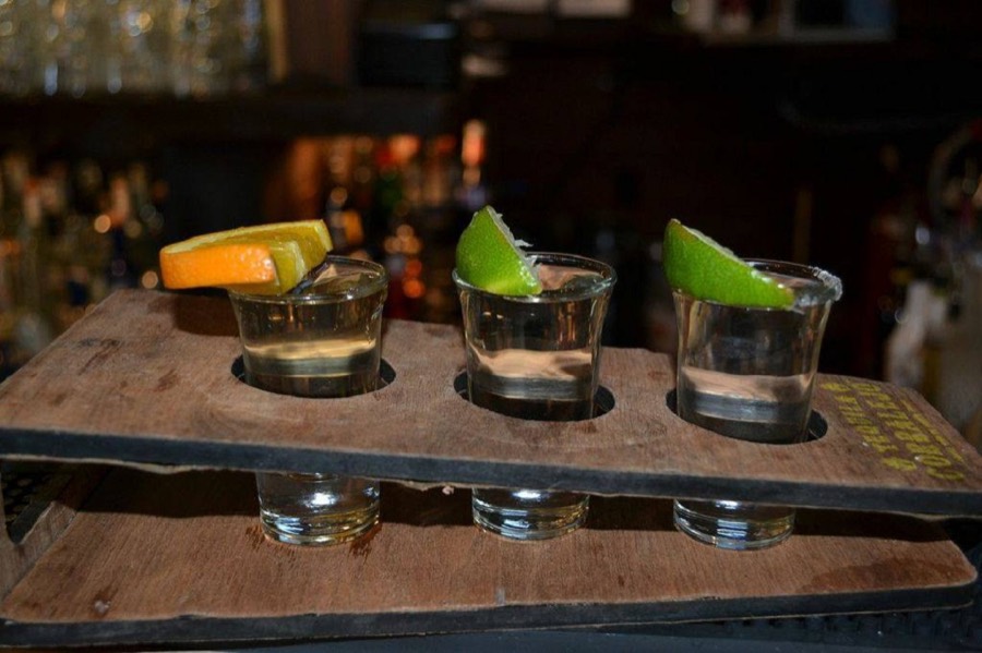 A flight of tequila shots with lime and orange